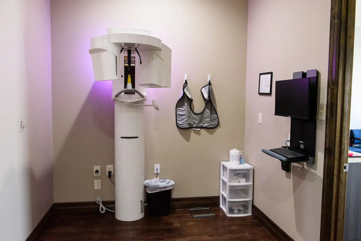 Panoramic dental X-ray room with imaging equipment, lead aprons, and workstation—highlighting advanced technology and commitment to safe, thorough dental diagnostics.