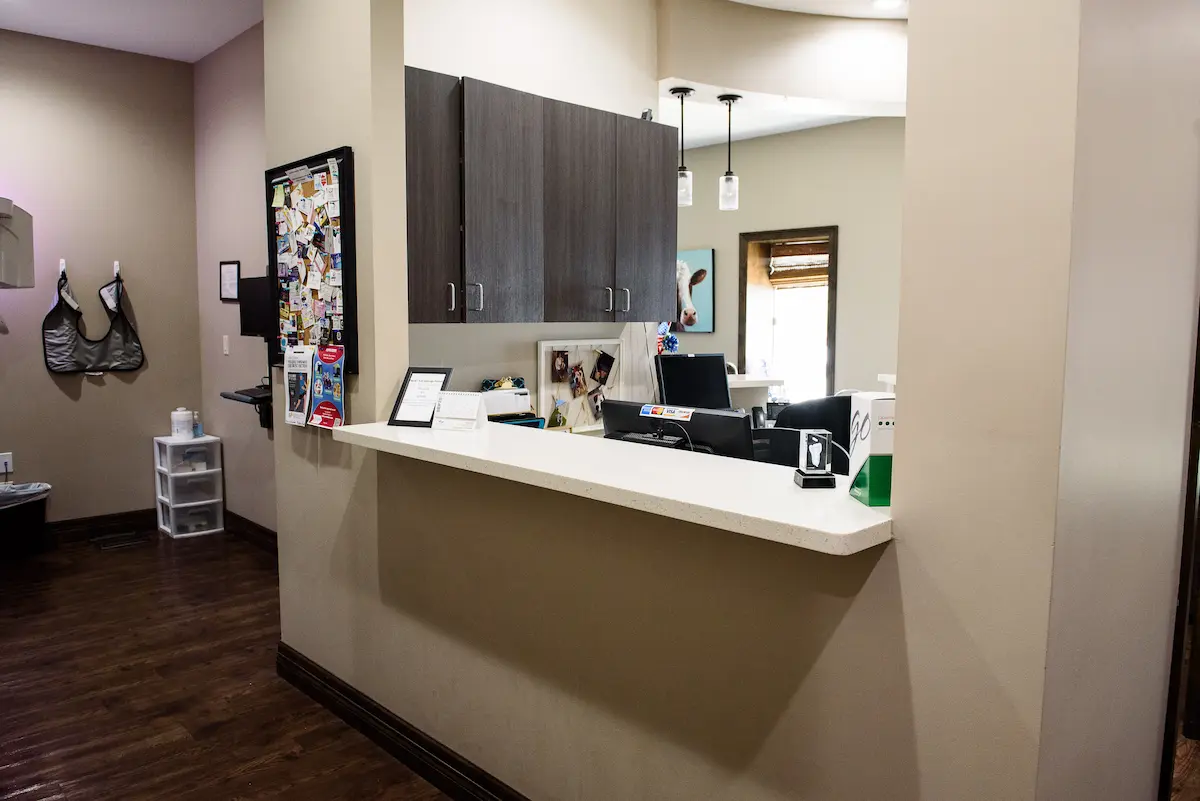 Dental office reception area with framed credentials, lead aprons, and organized cabinetry—highlighting a clean, professional environment focused on patient care and diagnostic readiness.