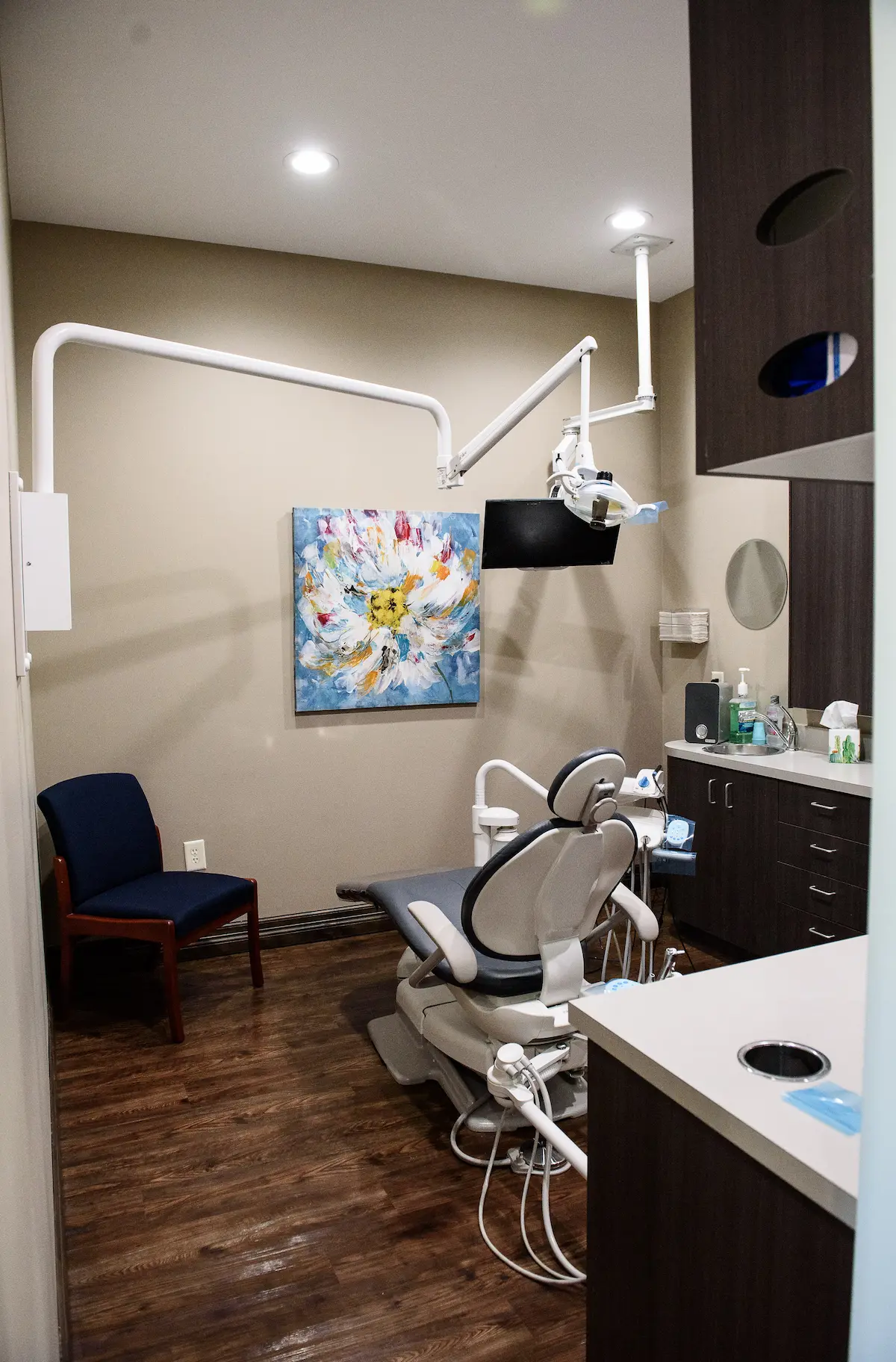 Dental exam room with patient chair, overhead monitor, and organized cabinetry—designed for modern, comfortable, and efficient dental care